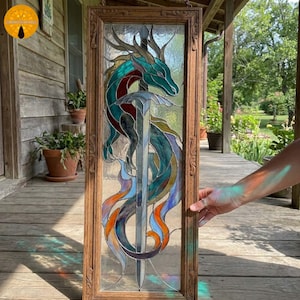 May include: Stained glass panel featuring a dragon wrapped around a sword. The dragon is teal, red, and blue, with a long, flowing tail. The sword is silver, and the panel is framed in a wooden border. The panel is approximately 12 inches wide and 24 inches tall.