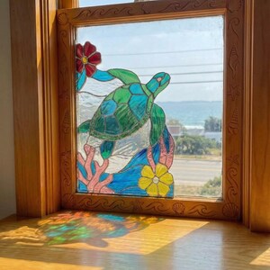 May include: Stained glass window panel featuring a sea turtle swimming above coral and flowers. The turtle is green and blue, with a detailed design. The window is framed in wood, with carved ocean-themed details.