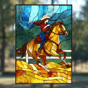 May include: Stained glass panel depicting a cowgirl riding a horse. The artwork features a woman in a red shirt and blue jeans, wearing a white hat, riding a brown and yellow horse. The background includes blue and green hues.