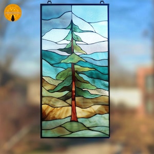 Könnte beinhalten: Buntglasfenster mit einem stilisierten Baum und Landschaft. Das Kunstwerk verwendet Grün-, Blau- und Brauntöne mit einem schwarzen Rahmen. Der Baum hat einen rotbraunen Stamm und grünes Laub, vor dem Hintergrund von Hügeln und Himmel.