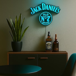 Op de afbeelding: Een neonbord met de tekst "Jack Daniel's" in het wit met een blauwe gloed. Twee whiskyflessen staan op een donkere houten kast. Een potplant en een kleine tafel zijn ook zichtbaar.