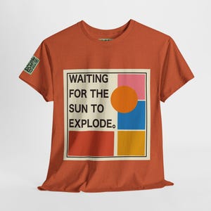 Puede incluir: Camiseta naranja quemada con formas geométricas de color naranja, rojo, amarillo, azul y rosa sobre un fondo beige. El texto "WAITING FOR THE SUN TO EXPLODE." está impreso en la camiseta.