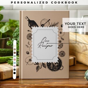 Può includere: Un libro di cucina personalizzato con la scritta "Our Recipes" in una cornice decorativa. La copertina è beige con illustrazioni nere di utensili da cucina e cibo. È visibile anche la scritta "Your Text Goes Here".