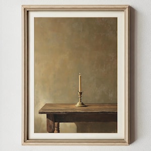 May include: A framed still life painting featuring a wooden table with a single lit candle in a brass candlestick. The artwork has a warm color palette with brown and gold tones, creating a vintage aesthetic. The frame is a light beige color.