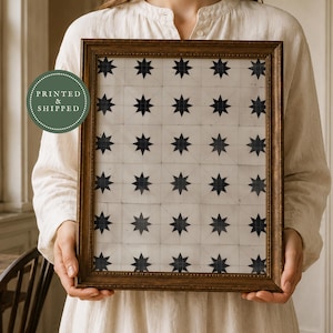 May include: A rectangular picture frame with a dark wood finish containing a print of a repeating grid pattern of black eight-pointed stars on a white background. A circular green emblem with the text PRINTED & SHIPPED is visible on the left.