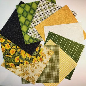 Könnte beinhalten: Auswahl an Stoffquadraten in verschiedenen Mustern und Farben. Enthält Blumen-, Karo-, Tupfen- und geometrische Designs in Gelb-, Grün-, Schwarz- und Weißtönen. Ideal für Quilt- oder Bastelprojekte.