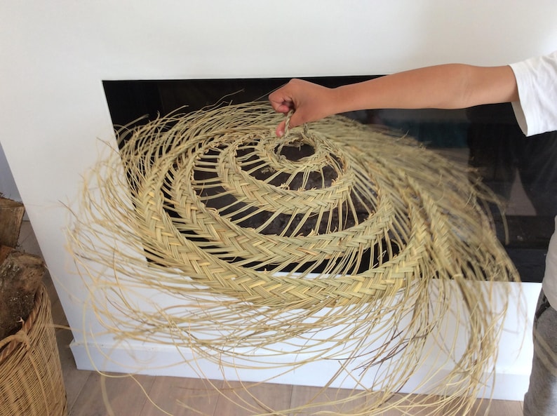 Puede incluir: Un sombrero grande, redondo, tejido de paja natural con una larga franja que fluye. El sombrero es de color marr&oacute;n claro y tiene un patr&oacute;n en espiral en el centro.