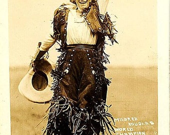 May include: A sepia-toned photo of a woman in a fringed leather outfit, holding a cowboy hat and raising her right arm in the air. The text on the photo reads "Millarer World's Champion Lady Bronco Buster."