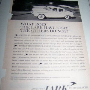 May include: A black and white vintage advertisement for the Studebaker Lark car. The ad features a photo of the car driving on a road and text that reads "What does the Lark have that the others do not?"  The ad highlights the car's fuel efficiency, performance, and six body styles.