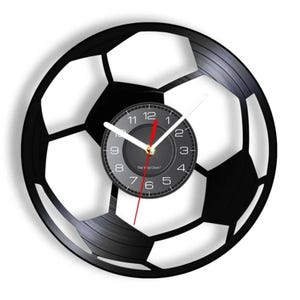 May include: A black vinyl record clock shaped like a soccer ball. The clock face is black with white numbers and hands. The text "The Vinyl Clock" is printed on the clock face.