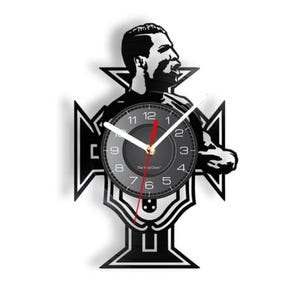 May include: Black and white vinyl record clock featuring a silhouette of a soccer player with the Portuguese national team crest. The clock face has black numbers and hands, with a red second hand.