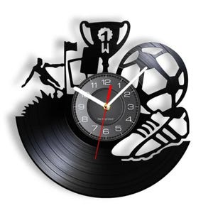 May include: Black vinyl record clock with a soccer ball, a trophy, a player, and a shoe design. The clock face is black with white numbers and hands.