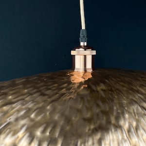 May include: A copper pendant light fitting with a hammered metal shade. The shade has a textured, rippled surface.