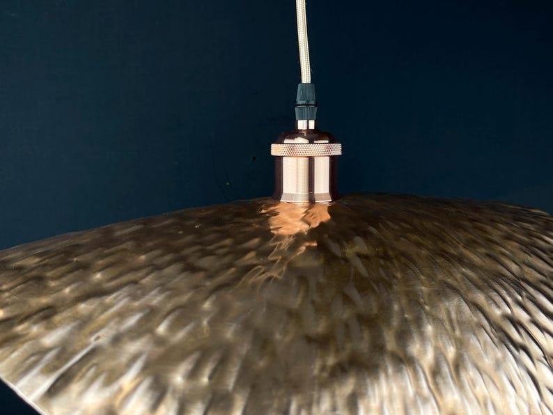 May include: A copper pendant light fitting with a hammered metal shade. The shade has a textured, rippled surface.