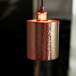 May include: A hammered copper pendant light fixture with a warm, glowing light bulb.