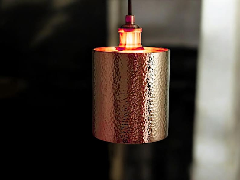 May include: A hammered copper pendant light fixture with a warm, glowing light bulb.