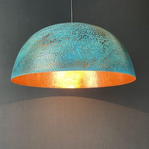 May include: A turquoise and copper dome-shaped pendant light fixture with a hammered texture.