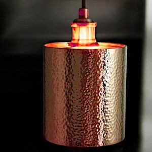 May include: A copper pendant light fixture with a hammered finish. The light is on and casting a warm glow.