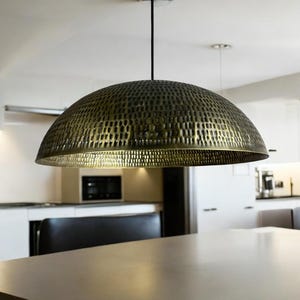 copper dome light fixture with detailed perforations hanging in modern dining area, showcasing the warm copper interior glow