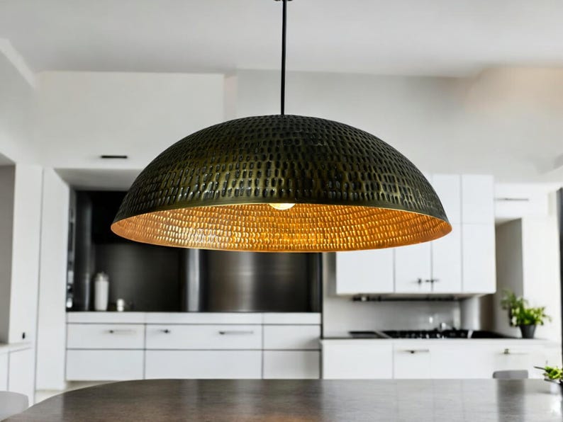 Perforated copper dome pendant with copper interior hanging in contemporary white kitchen, creating warm ambient lighting effect