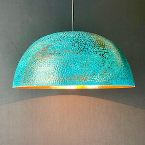 May include: A turquoise and gold pendant light with a hammered metal finish. The light is round and has a dome shape.