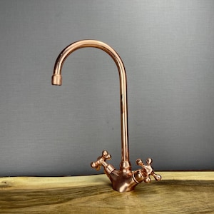 May include: A copper kitchen tap with a high arc spout and two cross-shaped handles.