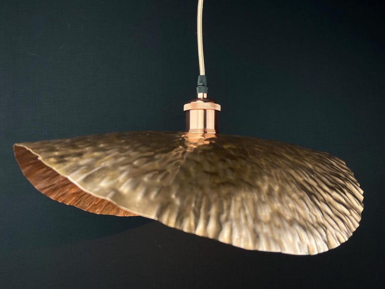 May include: A copper pendant light with a hammered, textured, and slightly wavy shade. The shade is a light gold colour and has a copper finish.