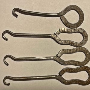 May include: Four vintage metal shoe button hooks with looped handles. The handles are stamped with text, including "Bond Street Spats" and "Wise's Shoes Are Better". The hooks are a silver color.