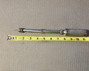 May include: A vintage metal awl tool with a wooden handle. The awl is approximately 11 inches long, with a sharp, pointed tip. A yellow measuring tape is placed next to the awl.