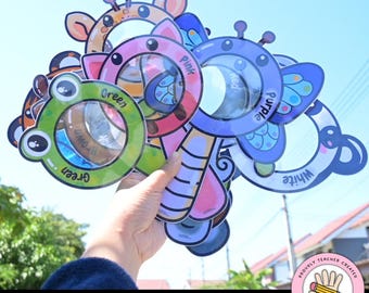 May include: A selection of colourful magnifying glasses in animal shapes, including a frog, giraffe, and butterfly. Each magnifying glass is labelled with a different colour, such as green, pink, and purple. The text "Magnifying Colors" is at the bottom.