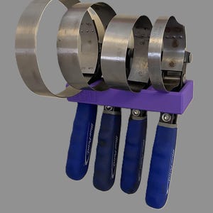 May include: A set of automotive filter wrenches. The wrenches are made of silver metal and have a circular design. They are attached to a purple holder with blue handles that have the "Blue-Point" logo.