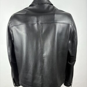 Pu&ograve; includere: Giacca in pelle nera con colletto classico e polsini con bottoni. La giacca ha una vestibilit&agrave; sartoriale e dettagli di cucitura visibili. Il retro della giacca &egrave; visibile, mostrando le cuciture e il design.