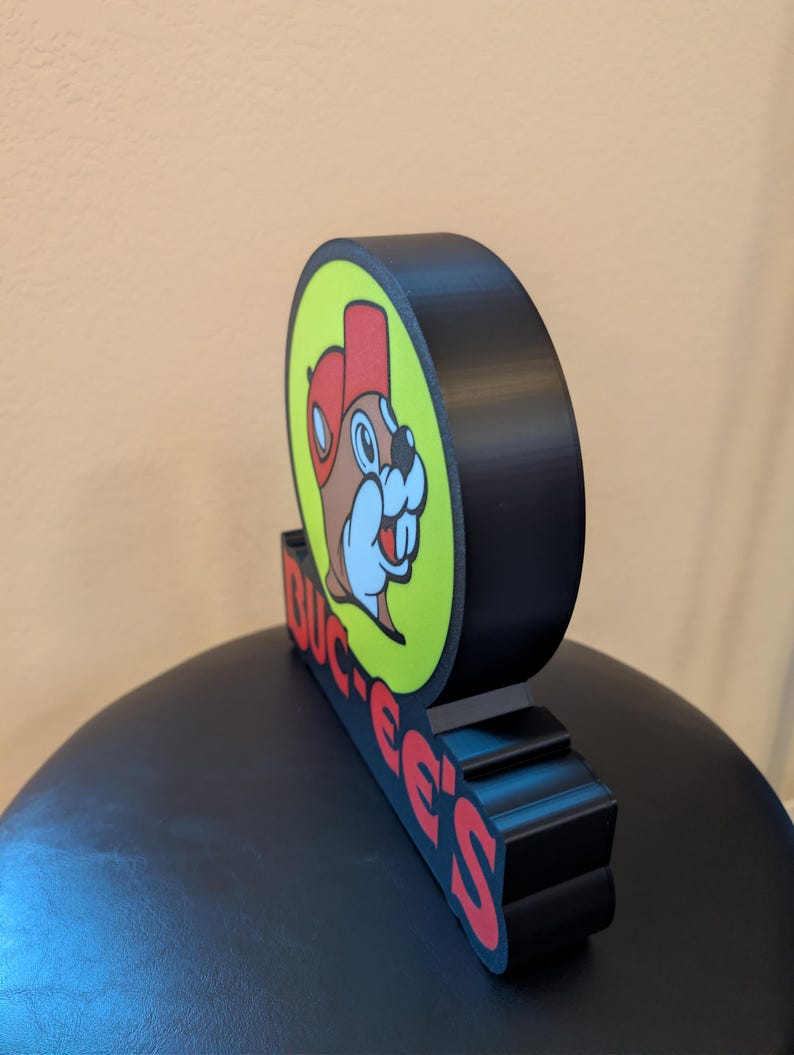 May include: A white ceramic mug with a black handle and the text "But First, Coffee" in a black, handwritten-style font. The mug is on a white surface.