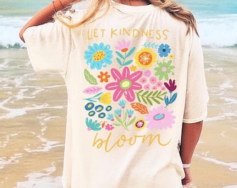 May include: White oversized t-shirt with a colorful floral design and the text "Let Kindness Bloom" printed on the back.