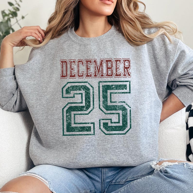 Pu&ograve; includere: Una felpa grigio melange con la scritta "DECEMBER 25" in stile vintage usurato. La parola "DECEMBER" &egrave; rossa e il numero "25" &egrave; verde. La felpa &egrave; a girocollo.
