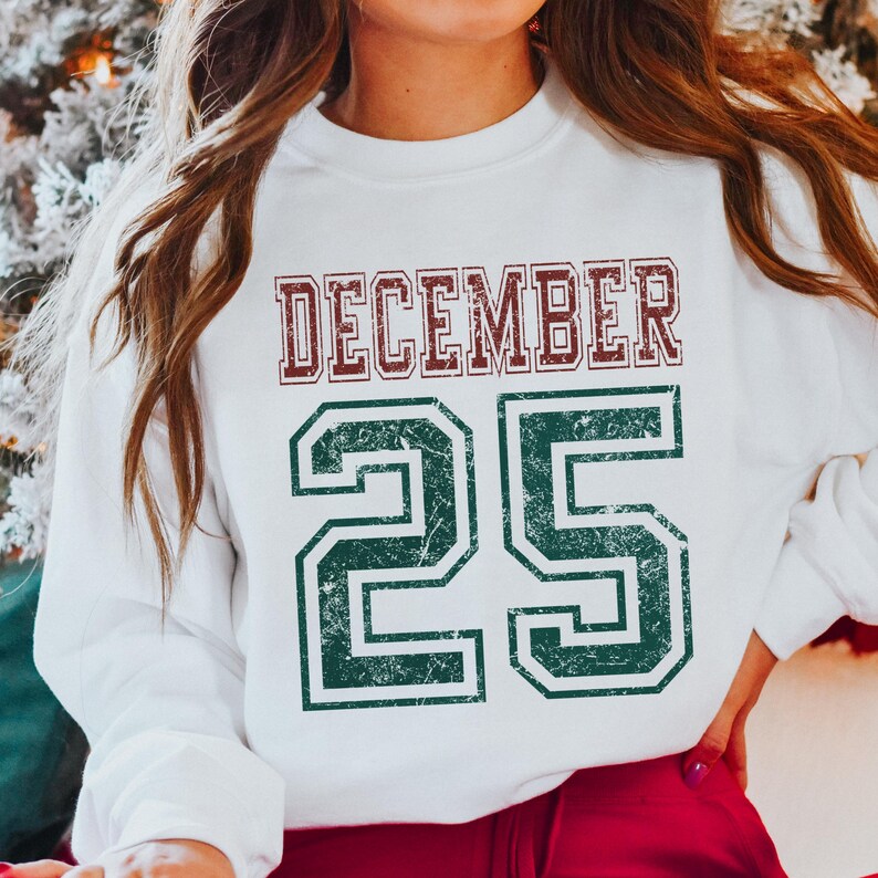 Pu&ograve; includere: Felpa bianca con la scritta "DECEMBER 25" in stile collegiale usurato. La parola "DECEMBER" &egrave; bordeaux e il numero "25" &egrave; verde. Un capo festivo per le vacanze natalizie.