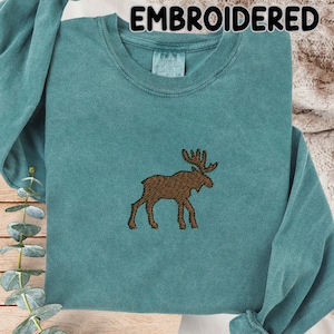 May include: Teal long-sleeve sweatshirt with an embroidered brown moose design. The word "EMBROIDERED" is printed at the top of the image. The sweatshirt has a crew neck and a relaxed fit.