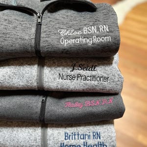 May include: Four gray fleece jackets with embroidered names and job titles. The top jacket says "Chloe BSN, RN Operating Room", the second says "J. Seidl Nurse Practitioner", the third says "Haley BSN RN", and the bottom says "Brittani RN Home Health".