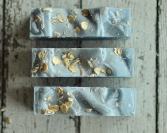 May include: Three bars of blue soap with oatmeal flakes embedded in the soap.