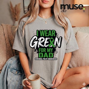 Op de afbeelding: Een grijs t-shirt met de tekst "I WEAR GREEN FOR MY DAD" in groen en wit, met een groene lintafbeelding. Het shirt is voor Cerebral Palsy Awareness.
