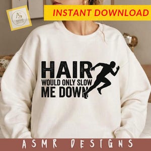 May include: A cream-colored crewneck sweatshirt featuring black text that reads HAIR WOULD ONLY SLOW ME DOWN, accompanied by a black silhouette graphic of a person running. The design is centered on the front of the garment.