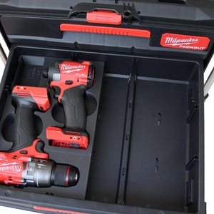 May include: Black and red Milwaukee Packout toolbox with two red and black FUEL power tools. The toolbox is open, revealing the tools in a fitted compartment. The Milwaukee logo is visible on the toolbox and tools.