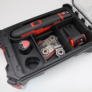 Könnte beinhalten: Ein schwarzes und rotes Elektrowerkzeug-Set mit verschiedenen Komponenten. Das Set enthält ein oszillierendes Multi-Tool, einen Akku und mehrere Klingen. Der Koffer ist schwarz mit einem transparenten Deckel.