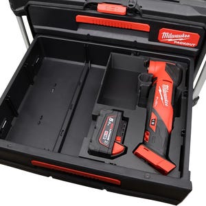 Può includere: Cassetta degli attrezzi Milwaukee Packout nera e rossa con un cassetto aperto. All'interno, sono visibili un multiutensile oscillante rosso e nero, una batteria 5.0 M18 e scomparti portaoggetti. Il logo Milwaukee è visualizzato sulla scatola.