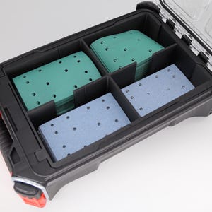 Puede incluir: Caja de herramientas negra y roja con tapa transparente, que contiene pilas de hojas de papel de lija verdes y azules. La caja de herramientas está dividida en compartimentos, ofreciendo un almacenamiento organizado para los suministros de lijado.