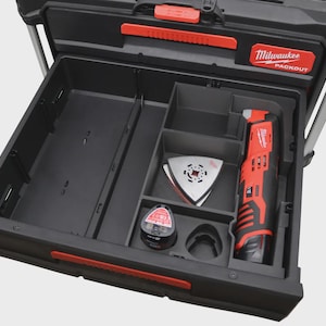 Puede incluir: Caja de herramientas Milwaukee Packout negra y roja con un cajón abierto. El cajón contiene una multiherramienta oscilante roja y negra, una cuchilla triangular y un accesorio circular. El logotipo de Milwaukee Packout es visible.