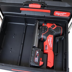 May include: A red and black Milwaukee Packout tool box with a red and black jigsaw and a red 5.0 Ah battery inside.