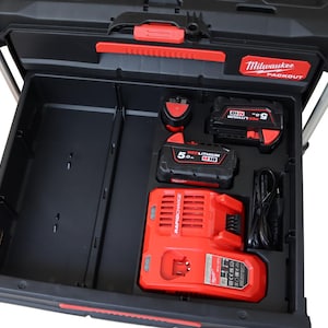 Pode incluir: Caixa de ferramentas Milwaukee Packout preta com detalhes vermelhos, aberta para revelar uma gaveta com um carregador rápido vermelho, duas baterias 5.0 Redlithium M18 e uma porta de carregamento. O logotipo Milwaukee Packout é visível.