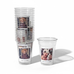 Peut inclure: Gobelets en plastique transparents, certains empil&eacute;s, avec des photos attach&eacute;es. Un gobelet porte une photo d'une personne portant un chapeau, avec le texte "The Groom". Un autre gobelet porte le texte "Wife of the Party".