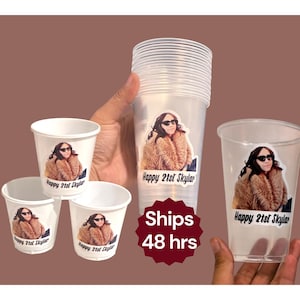 Può includere: Bicchieri di plastica trasparente e bicchieri di carta bianchi con un adesivo di una persona con occhiali da sole e cappotto di pelliccia. Il testo "Happy 21st Skylar" è stampato sui bicchieri.